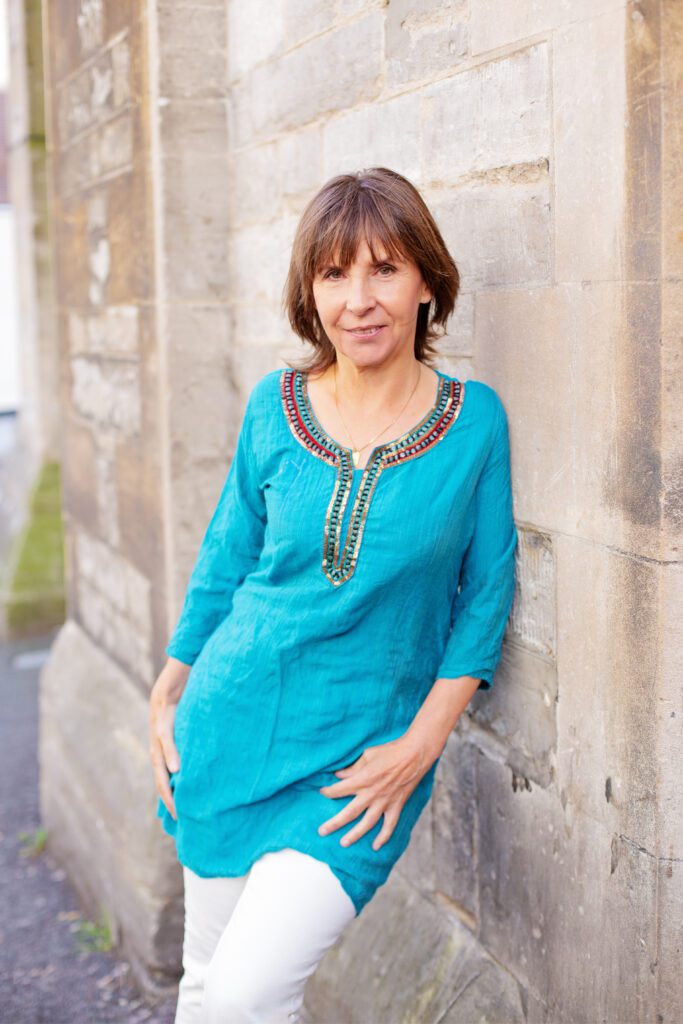 Suzan Wells standing outdoors reflecting on her yoga journey