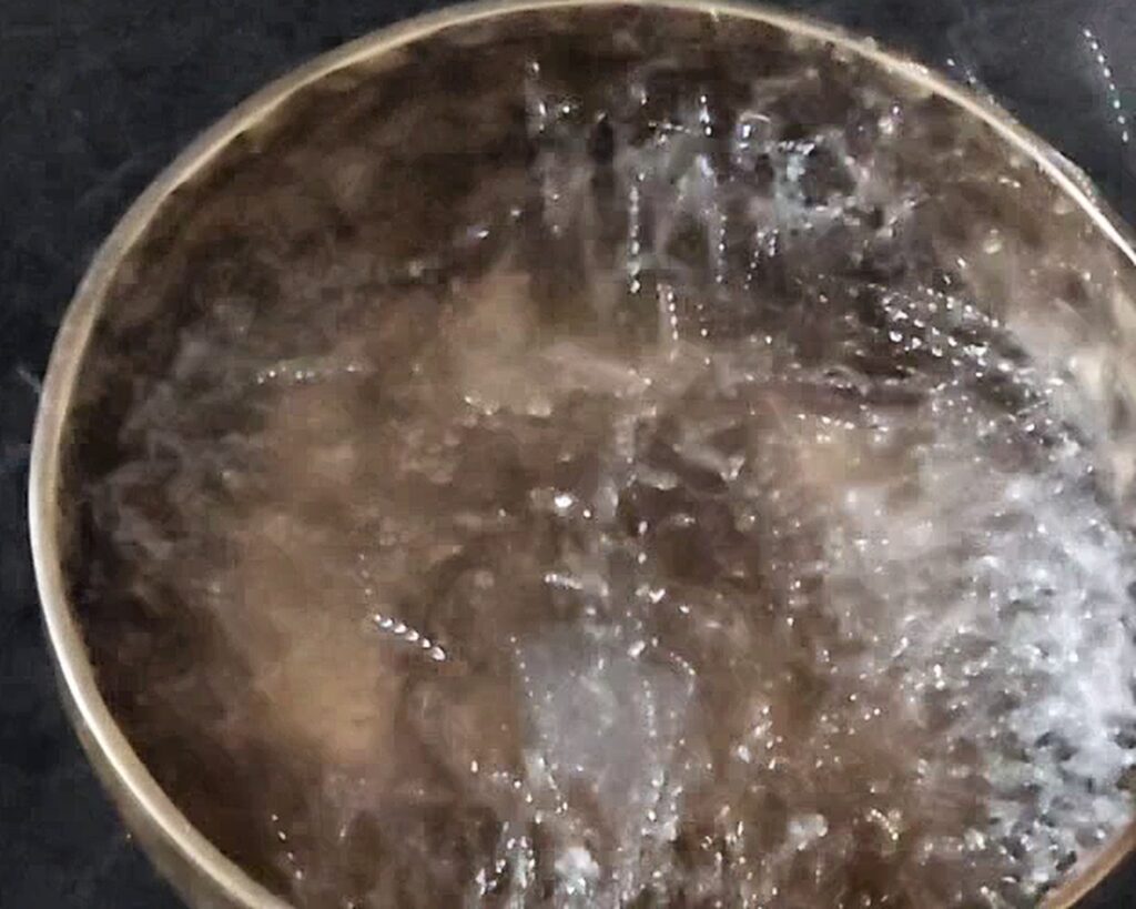 Ripples and reflected light moving across water in a singing bowl